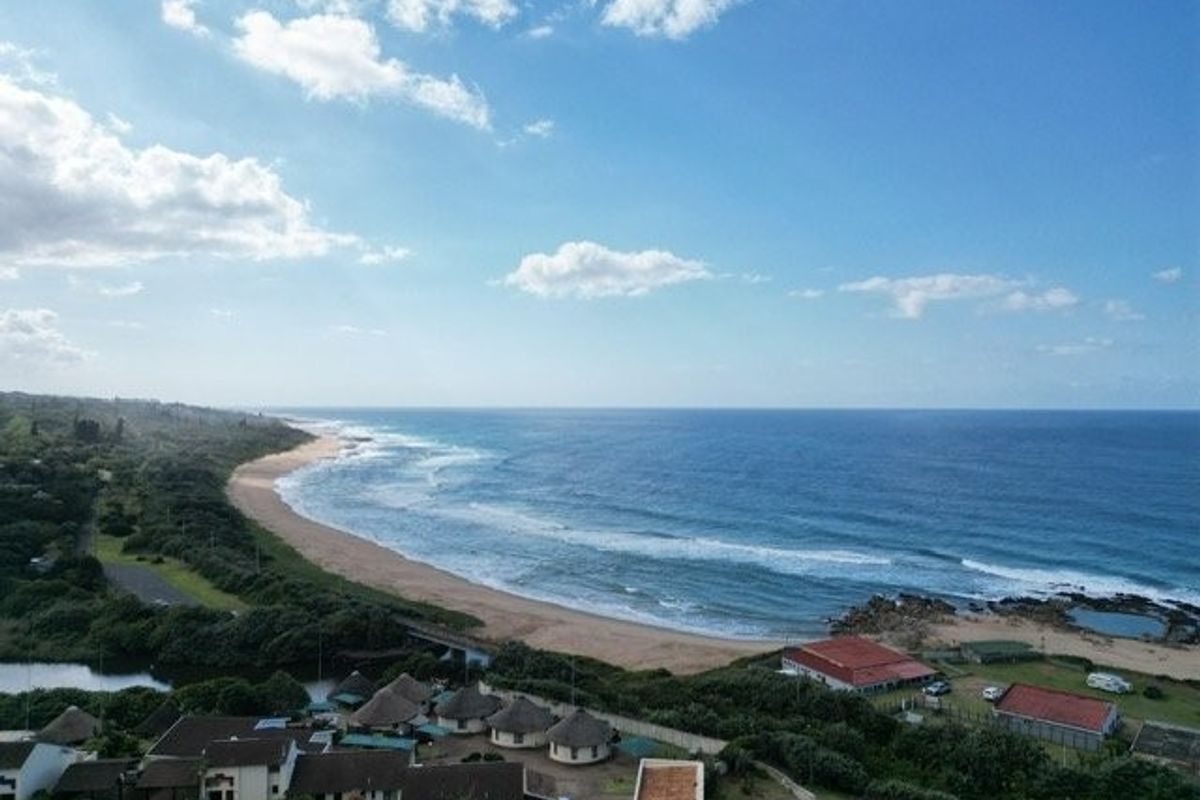 An aerial view showcasing the coastal landscape, sandy beach, and surrounding residential properties.