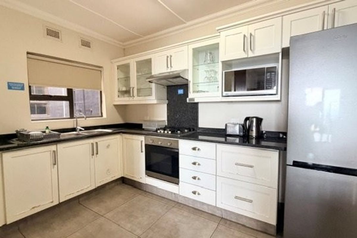 A functional kitchen featuring white cabinetry, granite countertops, built-in oven, gas hob, and integrated microwave, providing a clean and practical cooking space.