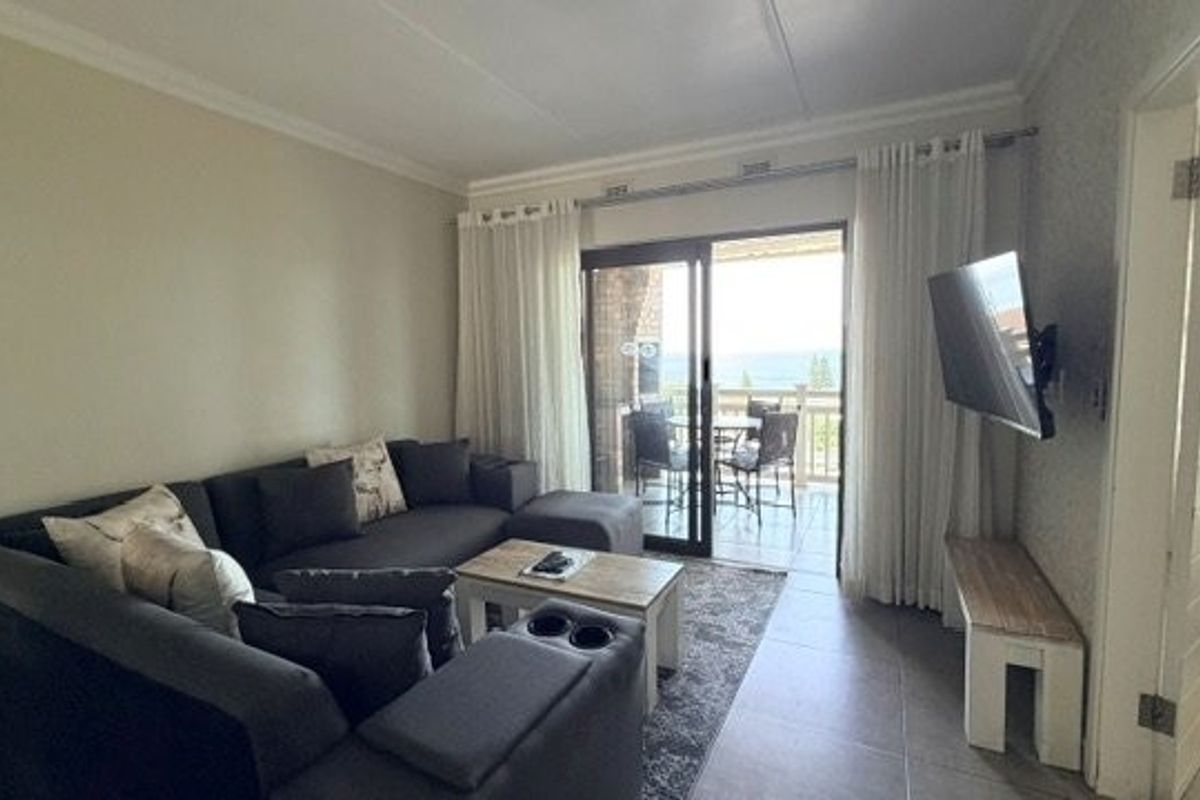 A comfortable living room featuring tiled flooring, cove cornicing, and a sliding glass door providing direct access to an outdoor balcony area.