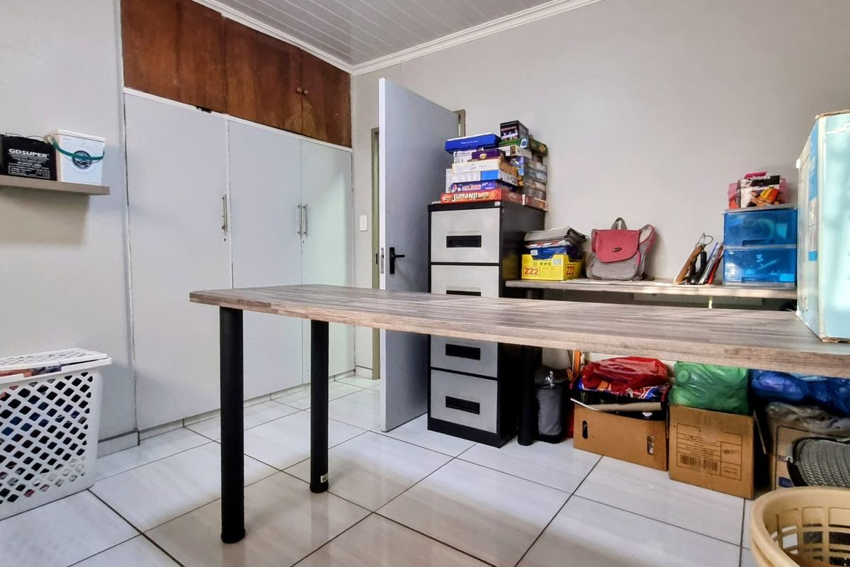 A functional bedroom or utility space featuring built-in floor-to-ceiling storage cupboards and tiled flooring.