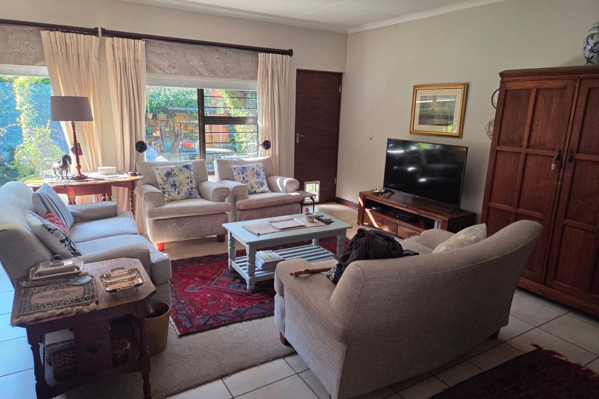 A comfortable living room featuring tiled flooring, large windows providing natural light, and a convenient pet door leading to the exterior.