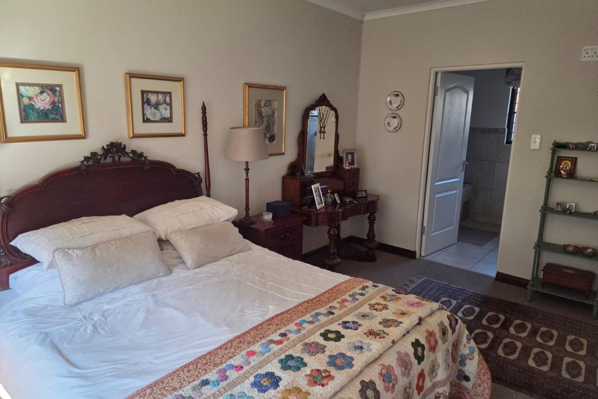 A well-maintained bedroom featuring carpeted flooring, coved ceilings, and direct access to an adjoining bathroom.