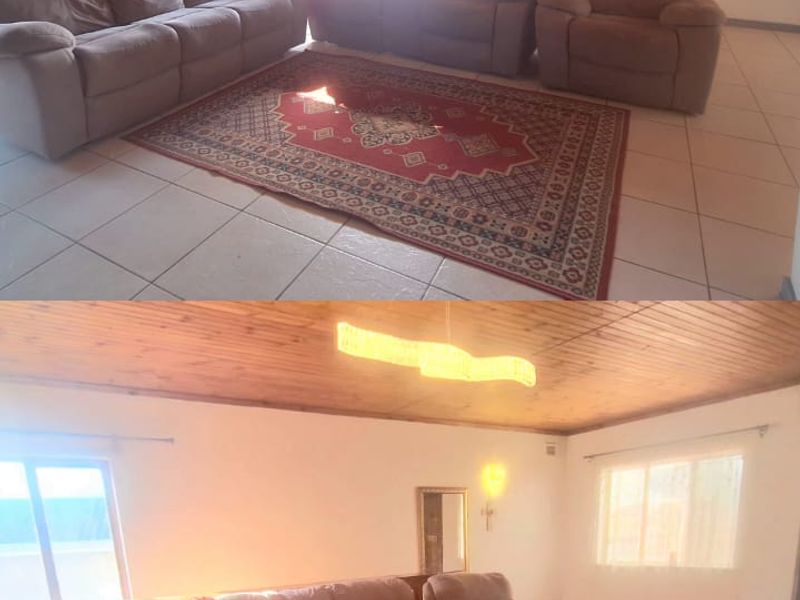 Spacious living room featuring a timber-clad ceiling, tiled flooring, and a timber balustrade, offering a warm and functional living space.