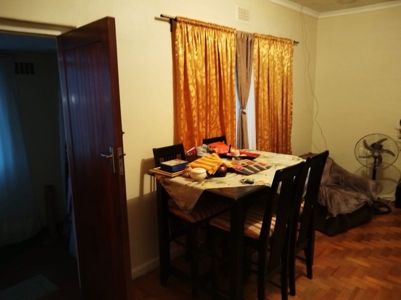 A dining area featuring classic parquet flooring and a solid timber door, providing a functional space for meals.