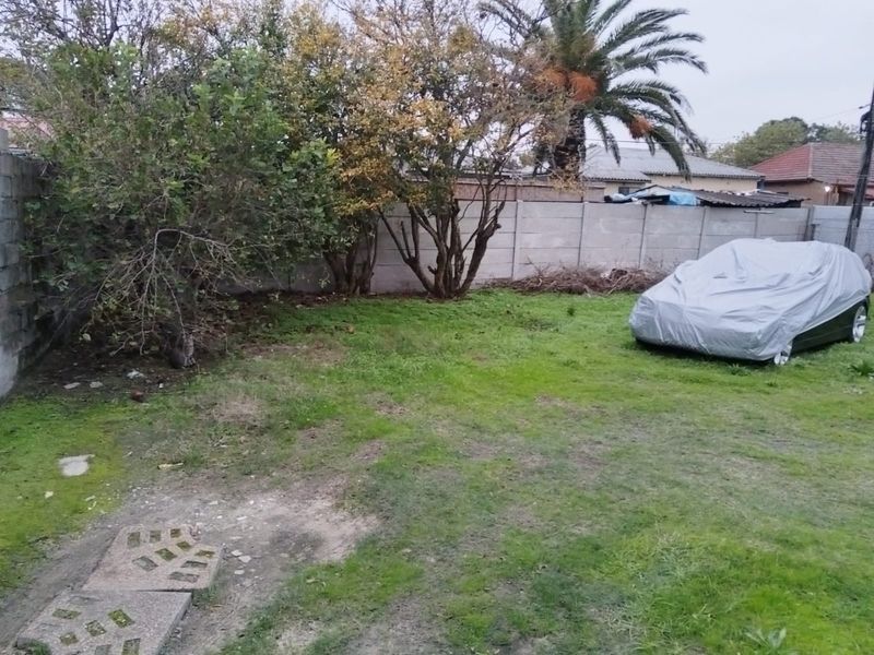 A private backyard area featuring a lawn and perimeter precast concrete walling, offering potential for landscaping and outdoor improvement.