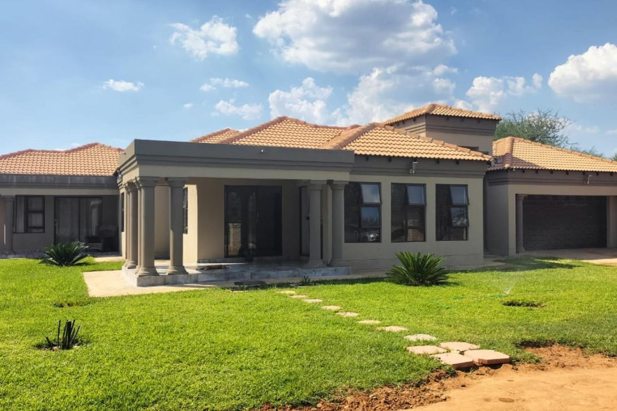 A well-maintained single-story residence featuring a covered patio with classical columns, terracotta roof tiles, and an attached garage set within a landscaped garden.