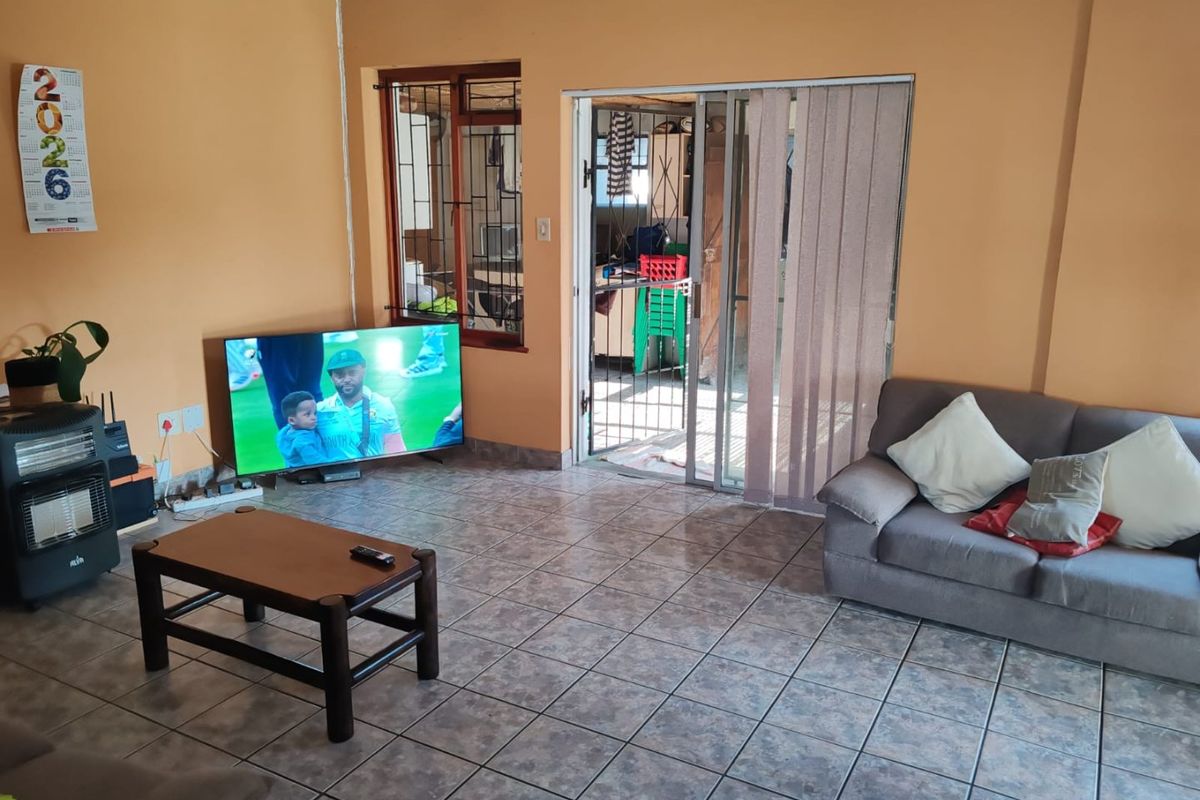 Living room featuring tiled flooring, a sliding glass door with security gate, and access to an adjacent outdoor area.