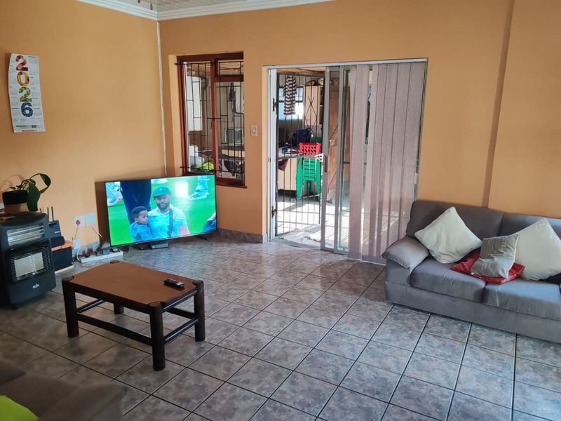Living room featuring tiled flooring, a sliding glass door with security gate, and access to an adjacent outdoor area.