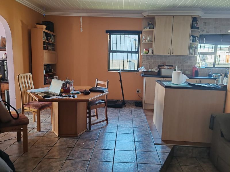 Open plan kitchen and dining area featuring tiled flooring, built-in cabinetry, and a central island, offering a functional layout with potential for cosmetic updates.