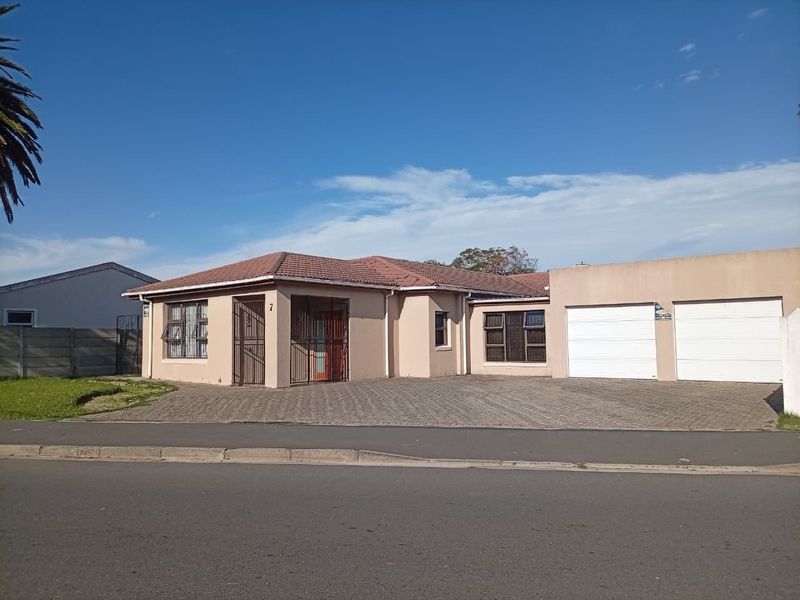 Front elevation of a single-story house featuring a tiled roof, paved driveway, and a double garage with security gates.