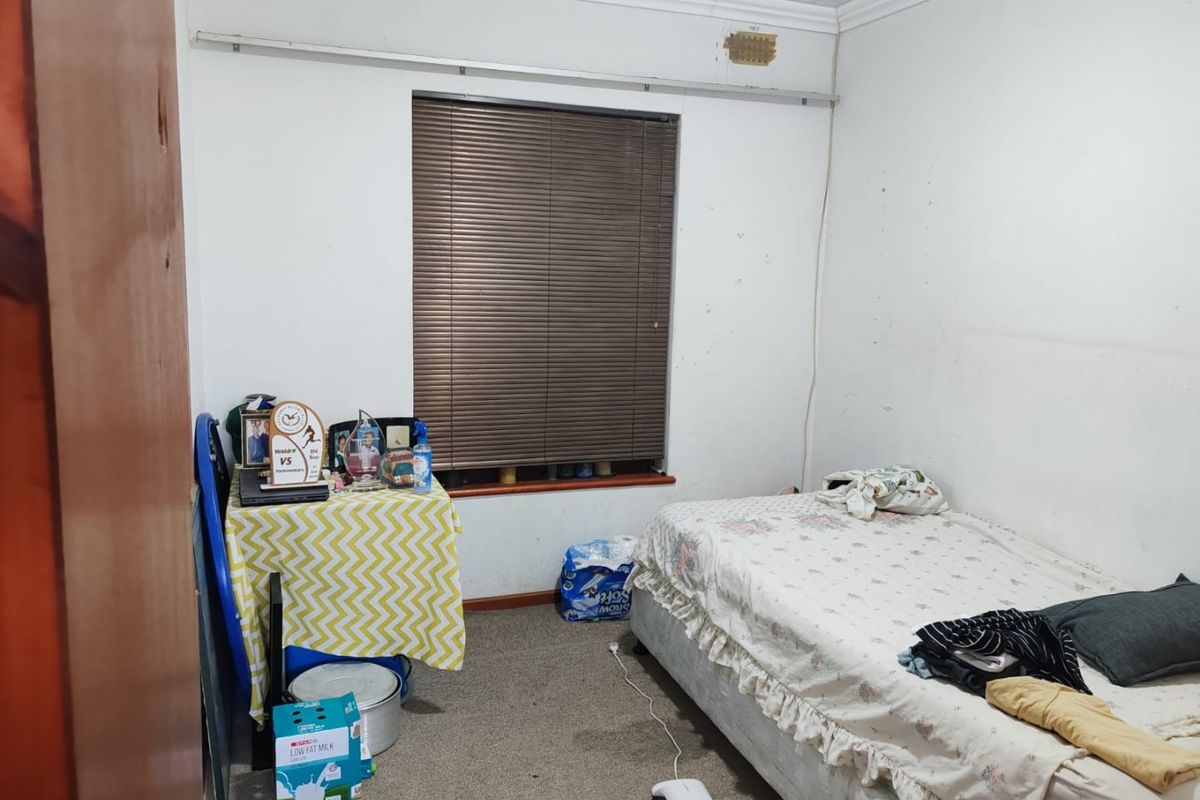 A bedroom featuring carpeted flooring, coved ceilings, and venetian blinds. The room requires cosmetic updates to the wall finishes and flooring.
