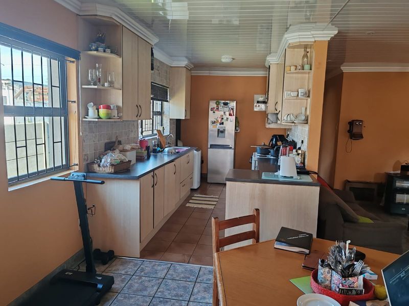 Open plan kitchen featuring laminate cabinetry, tiled backsplash, and tiled flooring, seamlessly connecting to the adjacent living area.