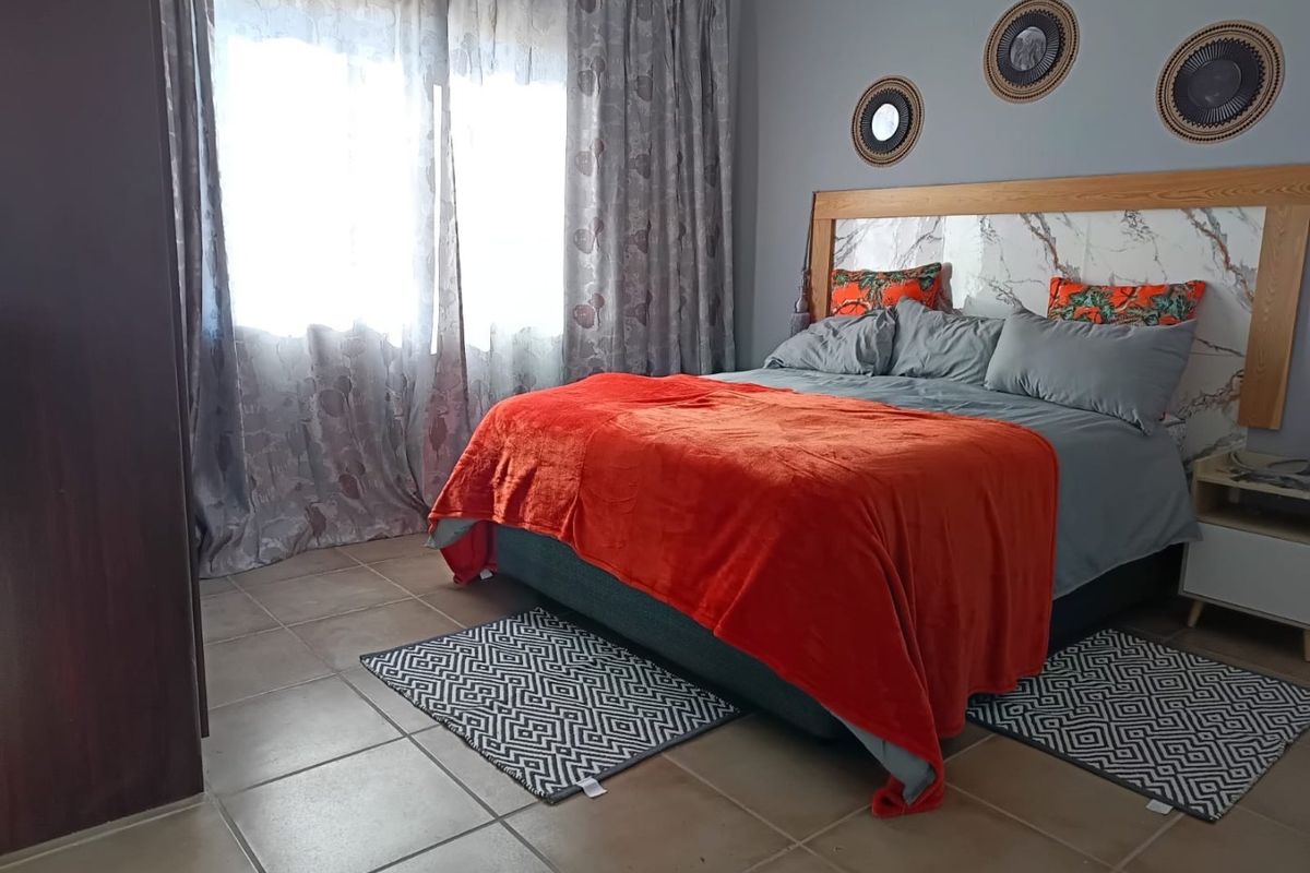 A well-maintained bedroom featuring tiled flooring and a modern built-in headboard with marble-effect detailing.