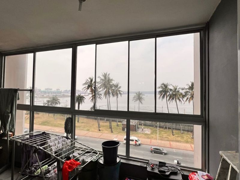 Enclosed balcony area featuring large sliding windows with expansive coastal and street views.
