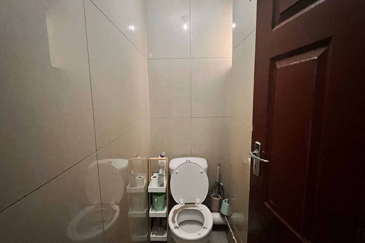 A compact guest bathroom featuring full-height wall tiling and a standard toilet fixture.