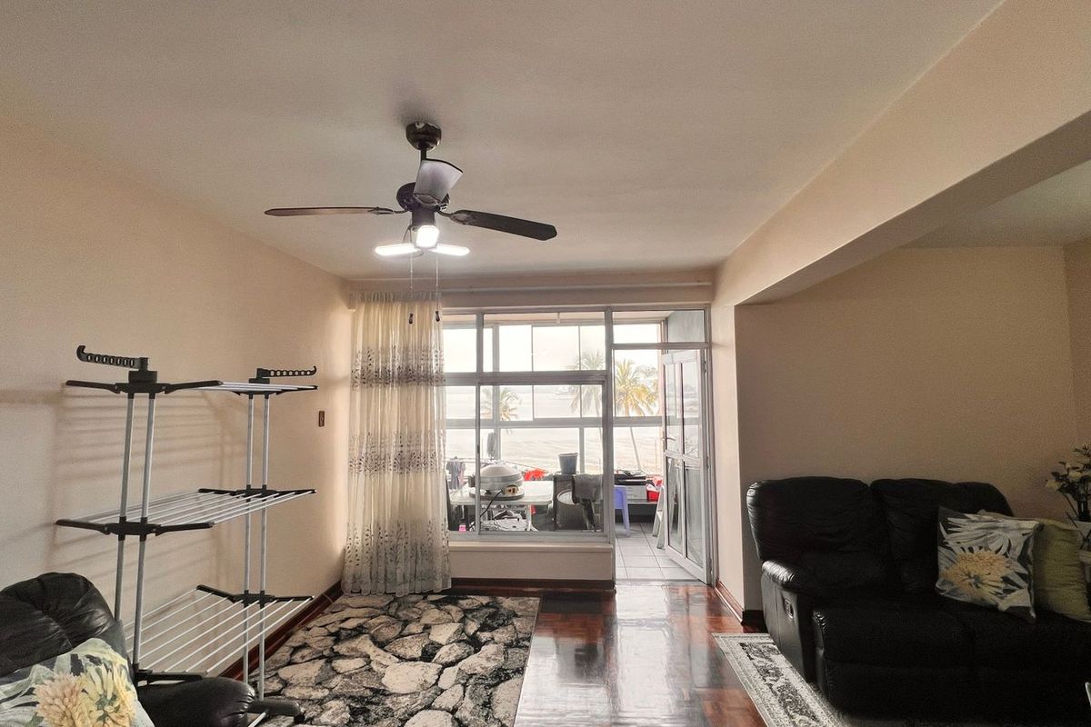 A living room featuring parquet flooring, a ceiling fan, and large windows providing natural light and access to an adjoining balcony.