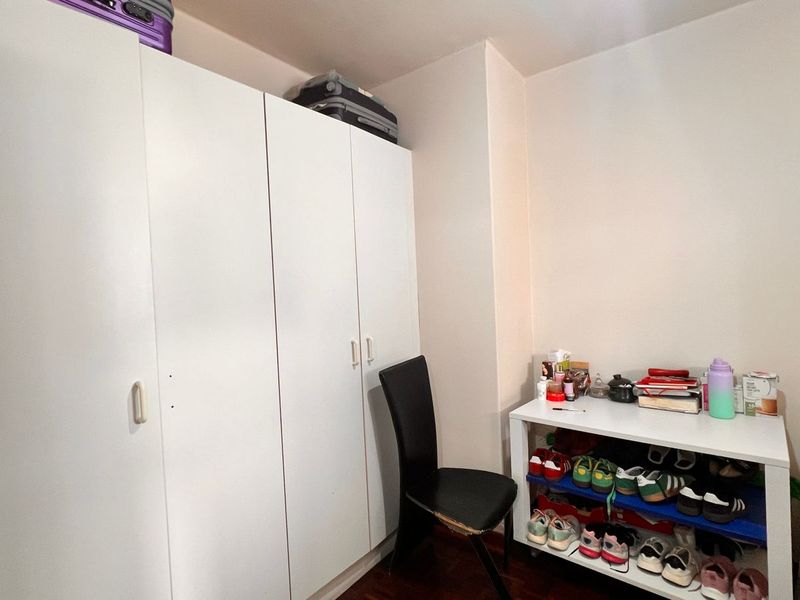 A bedroom featuring built-in white cabinetry and dark wood flooring, providing functional storage space within the apartment.