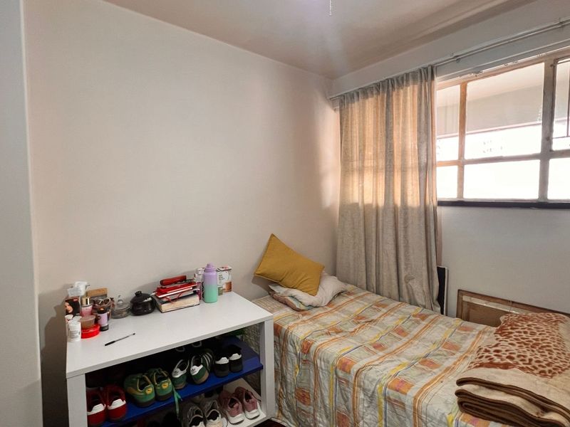 A functional bedroom featuring a window with security bars and neutral wall finishes.