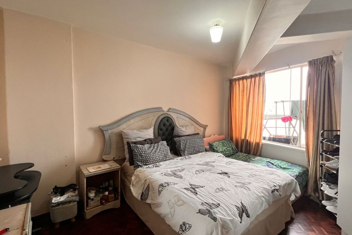A bedroom featuring parquet flooring, a large window with curtains, and a built-in wardrobe.