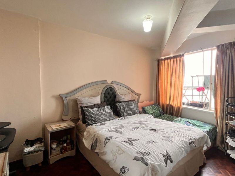 A bedroom featuring parquet flooring, a large window with curtains, and a built-in wardrobe.