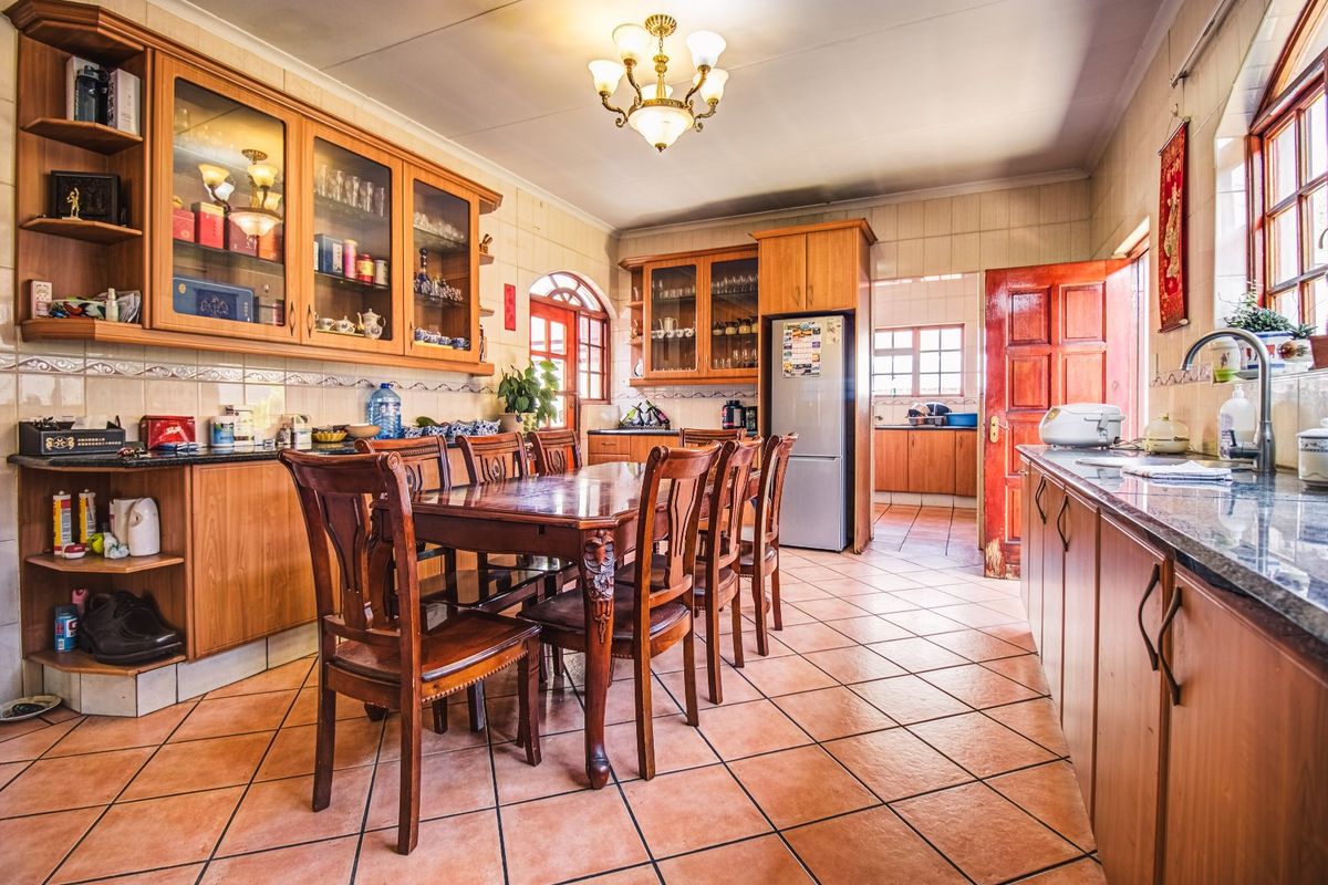 Spacious kitchen featuring extensive wooden cabinetry, granite countertops, tiled flooring, and a dedicated dining area, offering a functional layout with ample storage.
