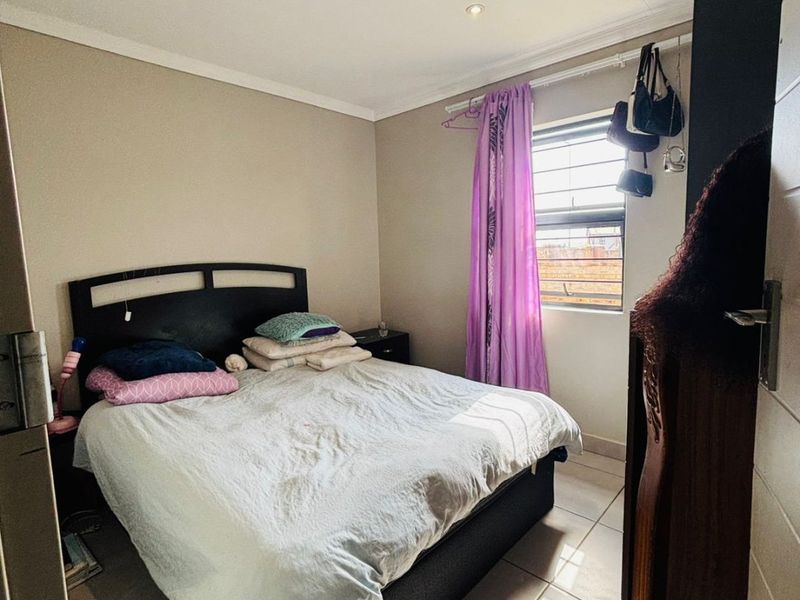 A functional bedroom featuring tiled flooring, recessed downlighting, and a window fitted with security bars.