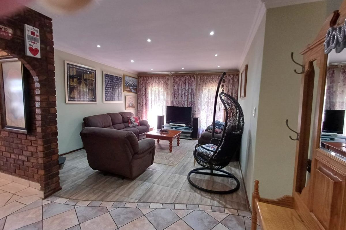 A comfortable living room featuring tiled flooring, recessed downlighting, and a distinctive exposed brick pillar, creating a warm and inviting atmosphere.