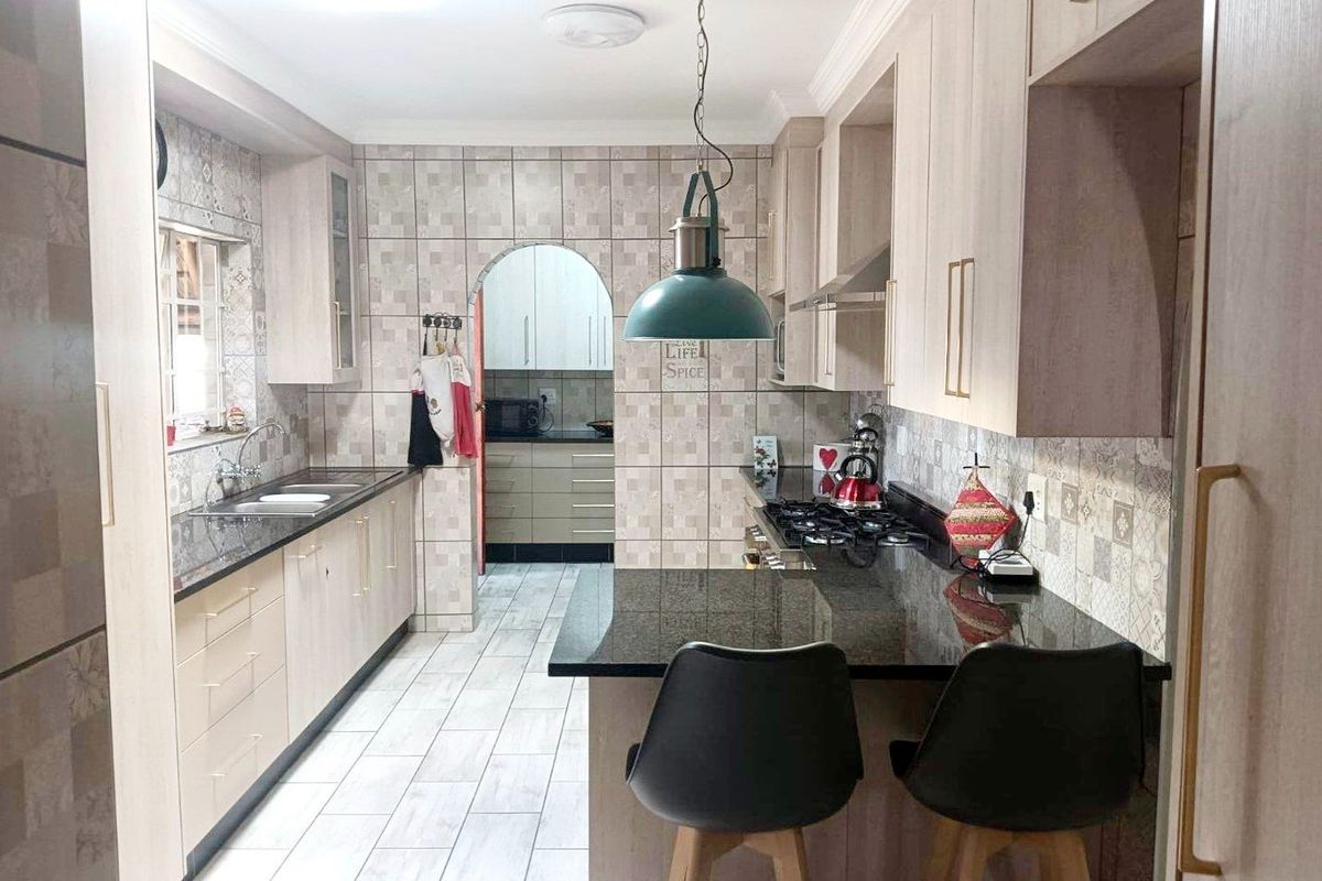 Modern kitchen featuring granite countertops, ample built-in cabinetry, a gas hob with extractor fan, and a functional breakfast bar area.