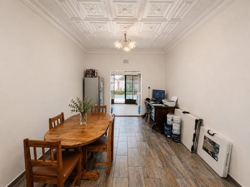 Dining room featuring wood-look tiled flooring and a decorative pressed metal ceiling, with direct access to the outdoor pool area through sliding glass doors.