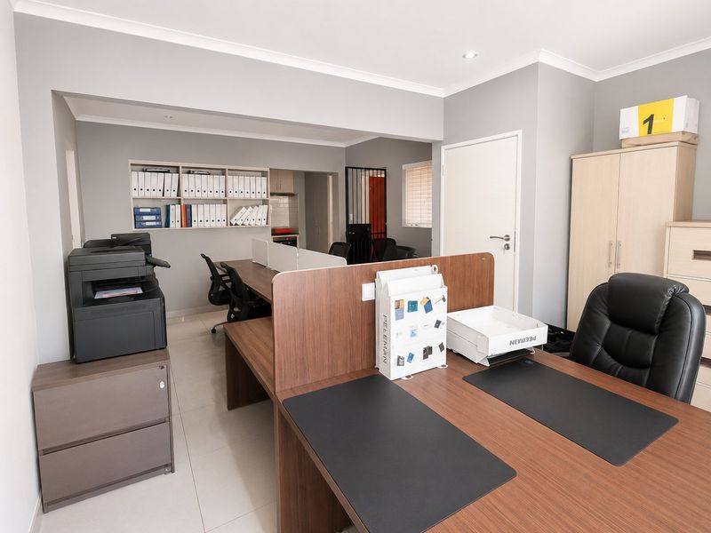 A functional office space featuring built-in shelving, tiled flooring, and recessed lighting, providing a clean and professional work environment.
