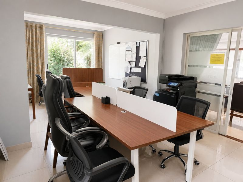 A functional office space featuring tiled flooring, large windows for natural light, and a sliding glass door entrance.