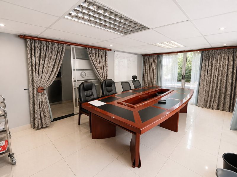 A professional office space featuring tiled flooring, a suspended ceiling with recessed lighting, and a sliding glass door leading to an adjacent area.