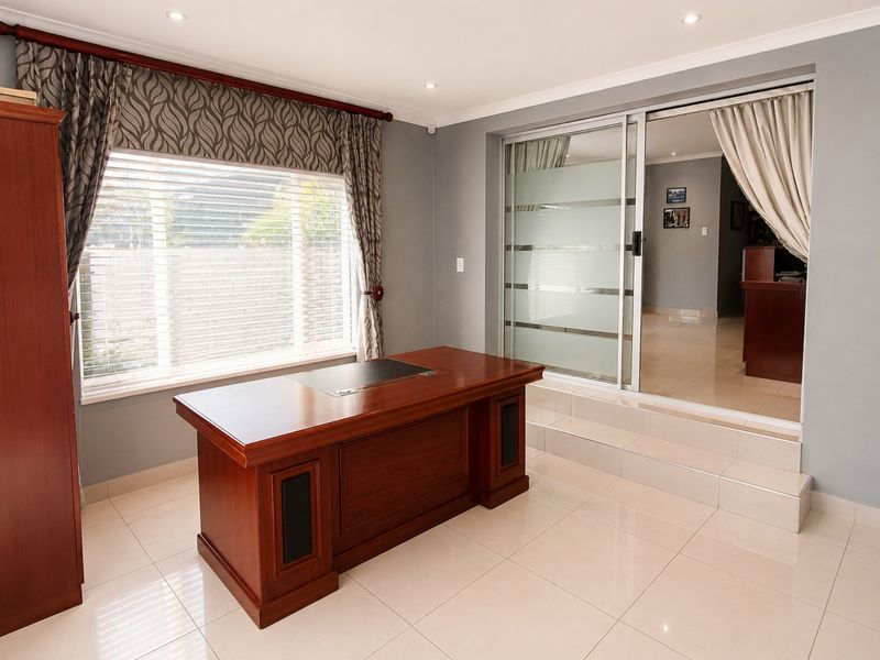 A well-lit home office featuring tiled flooring, recessed downlighting, and a sliding glass door providing access to the adjacent living area.