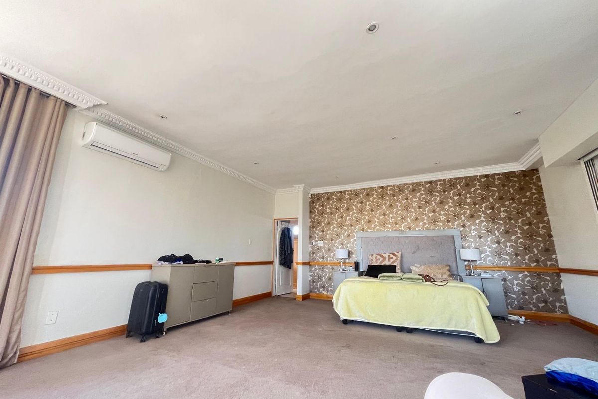 Spacious bedroom featuring crown molding, chair rail detailing, recessed lighting, and a wall-mounted air conditioning unit.