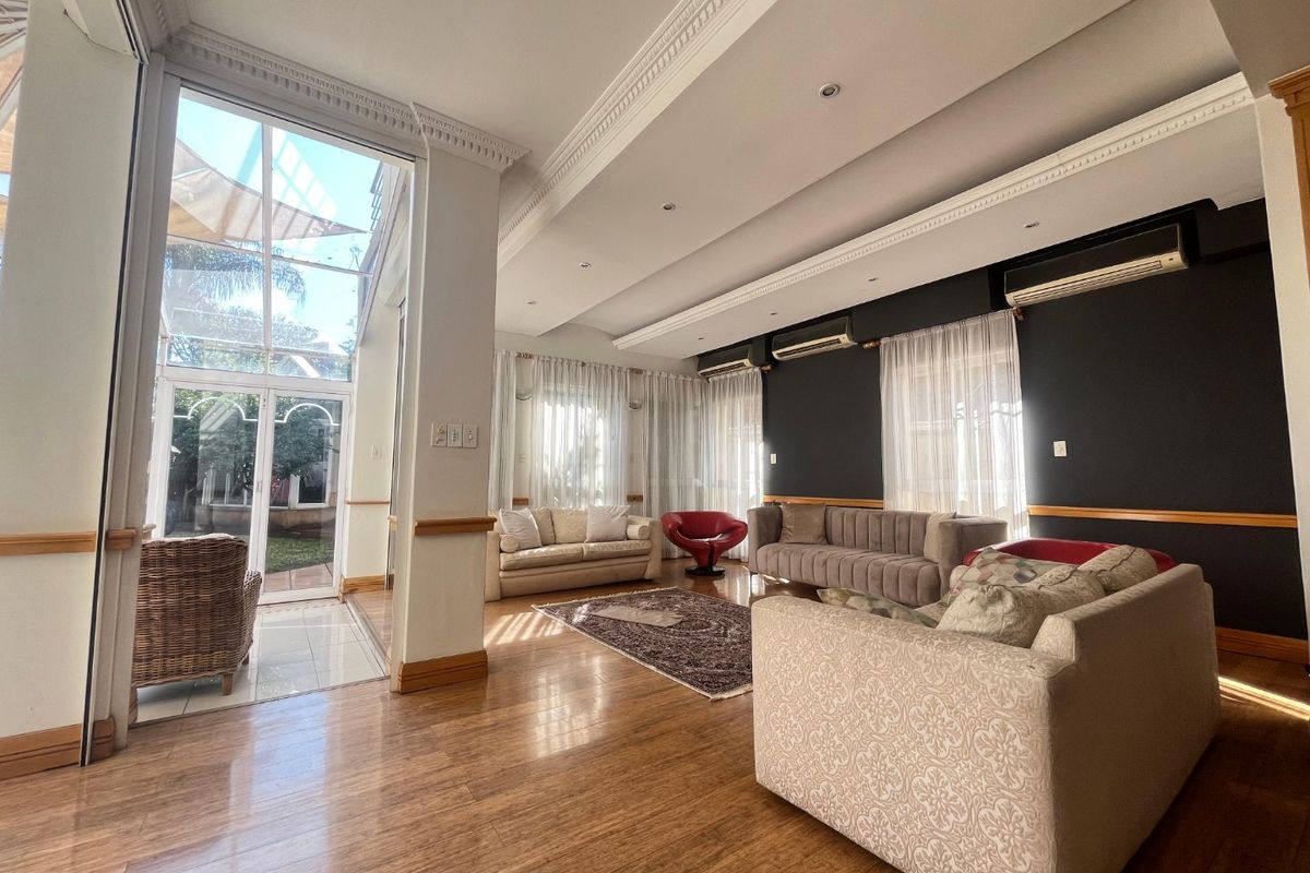Spacious living room featuring laminate flooring, crown molding, recessed lighting, and large glass doors providing ample natural light and access to the outdoor area.