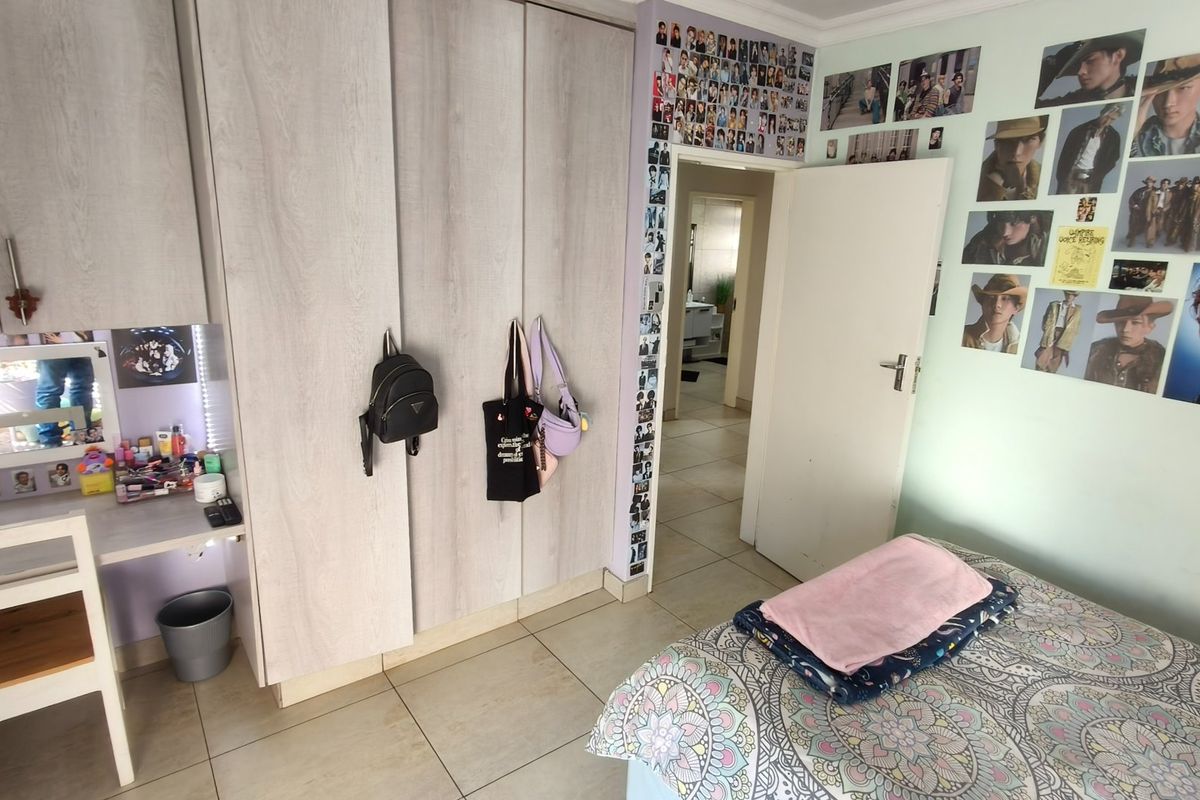A bedroom featuring built-in cupboards with an integrated vanity desk, tiled flooring, and direct access to an adjoining bathroom.