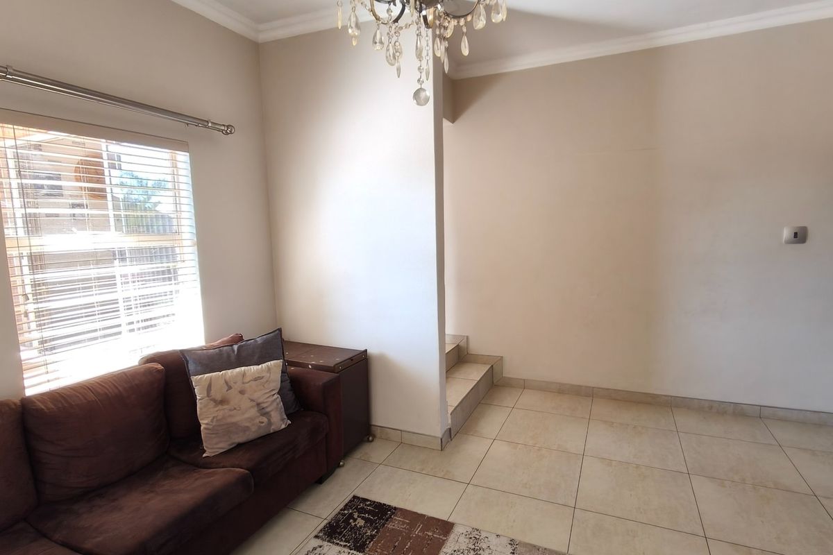 A living area featuring tiled flooring, crown molding, and a built-in staircase, offering a neutral foundation for interior design.