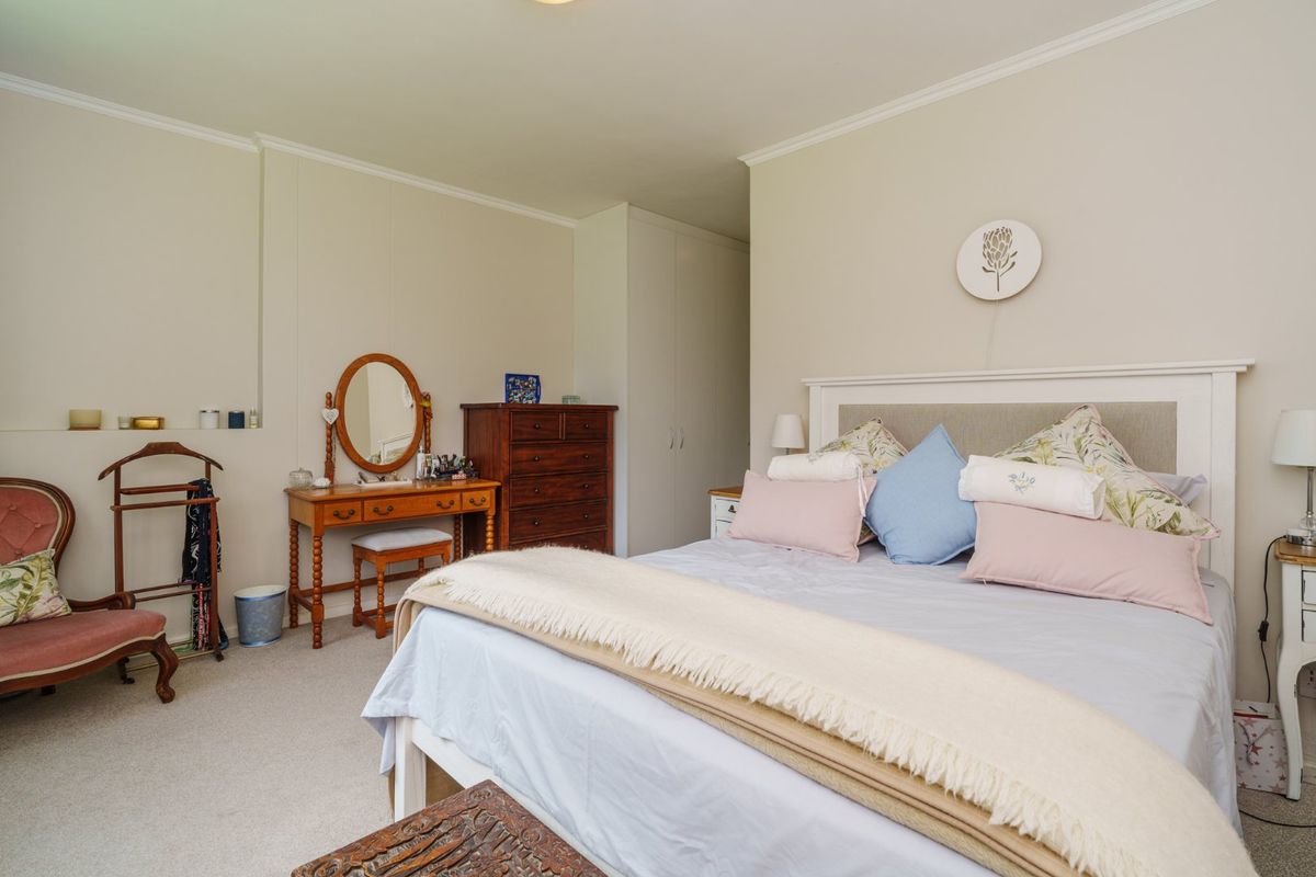 A well-maintained bedroom featuring neutral wall finishes, built-in storage cupboards, and carpeted flooring.