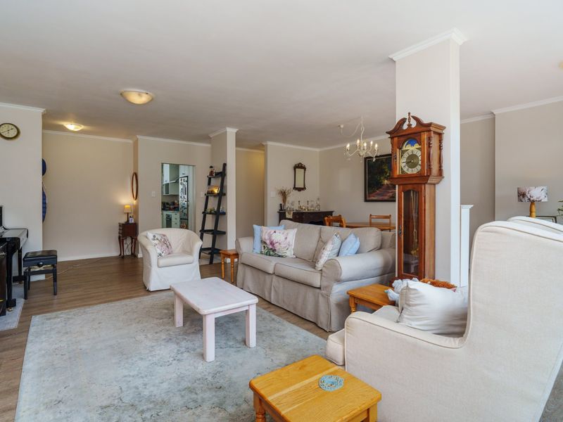 Spacious open-plan living and dining area featuring neutral walls, laminate flooring, and a central structural column, offering a versatile layout for modern living.