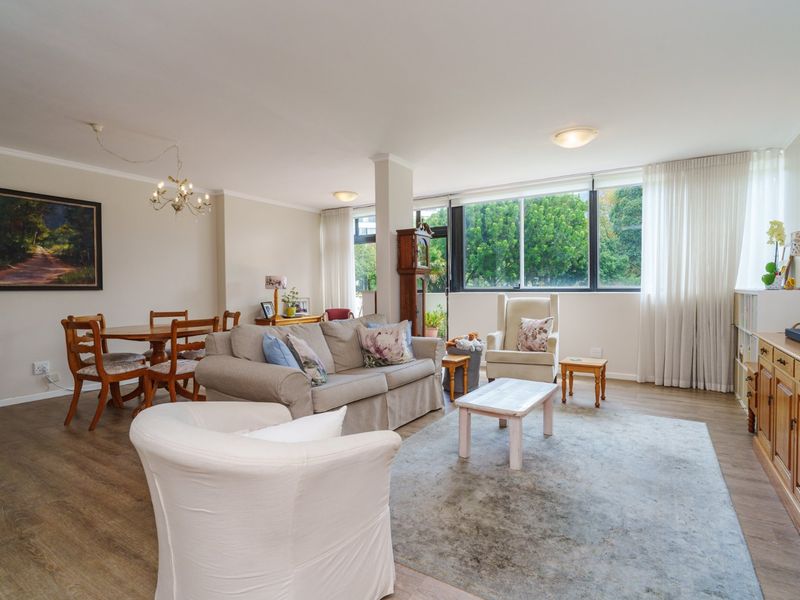 Spacious open-plan living and dining area featuring large windows, laminate flooring, and neutral wall finishes, offering a bright and versatile living space.