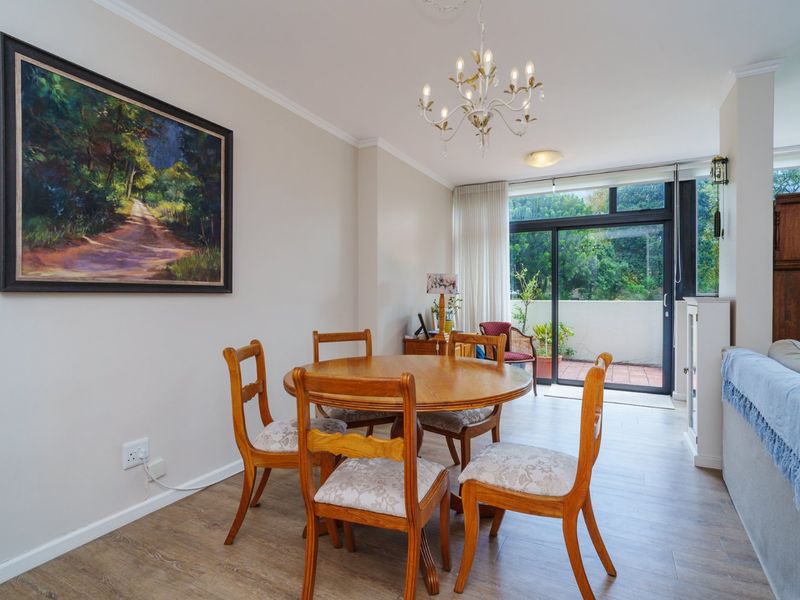 Bright dining area featuring laminate flooring, a decorative ceiling rose, and large sliding glass doors providing access to an outdoor patio space.