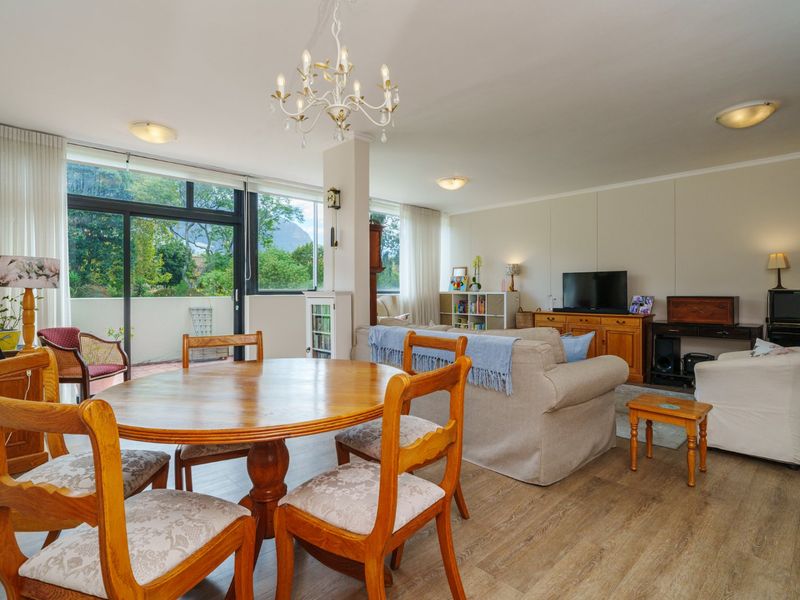 Spacious open-plan living and dining area featuring laminate flooring, large sliding glass doors leading to a balcony, and ample natural light.