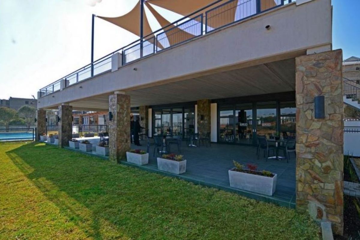 Spacious covered patio area featuring stone-clad pillars, tiled flooring, and direct access to the garden through large glass sliding doors.