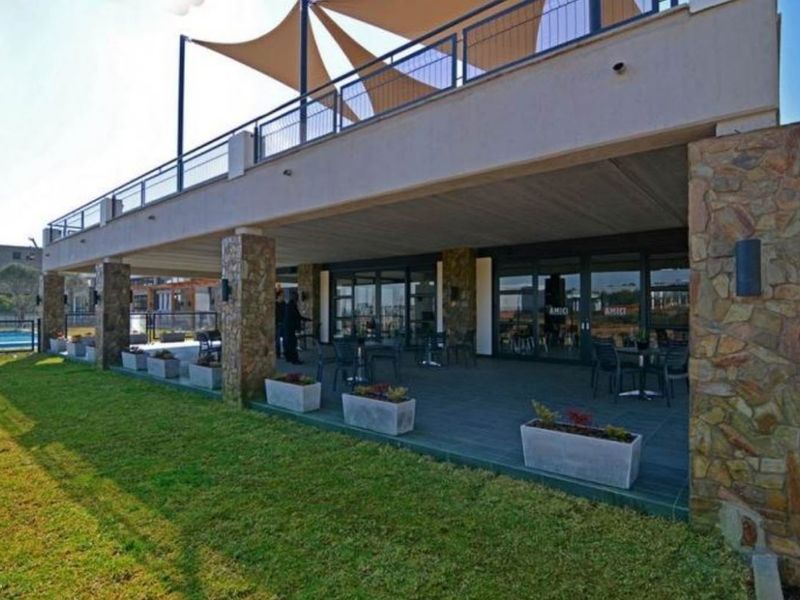 Spacious covered patio area featuring stone-clad pillars, tiled flooring, and direct access to the garden through large glass sliding doors.