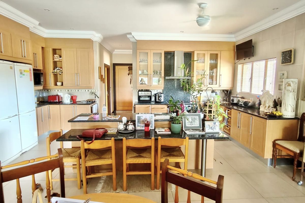 Spacious kitchen featuring light wood cabinetry, granite countertops, a central island with breakfast bar seating, and integrated appliances.