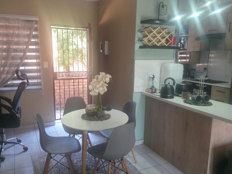 Open-plan living and kitchen area featuring modern cabinetry, a breakfast island, tiled flooring, and direct access to an exterior security gate.