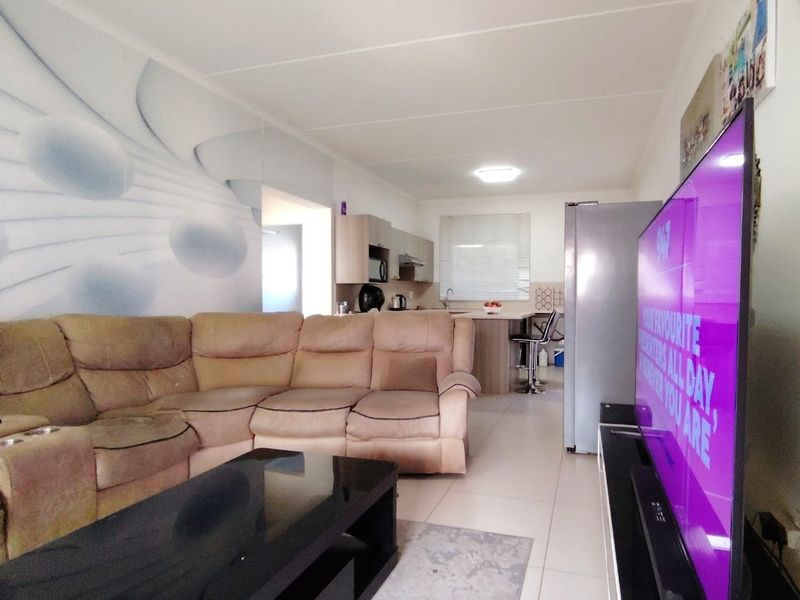 Open-plan living area featuring a combined lounge and kitchen space with tiled flooring and neutral cabinetry.