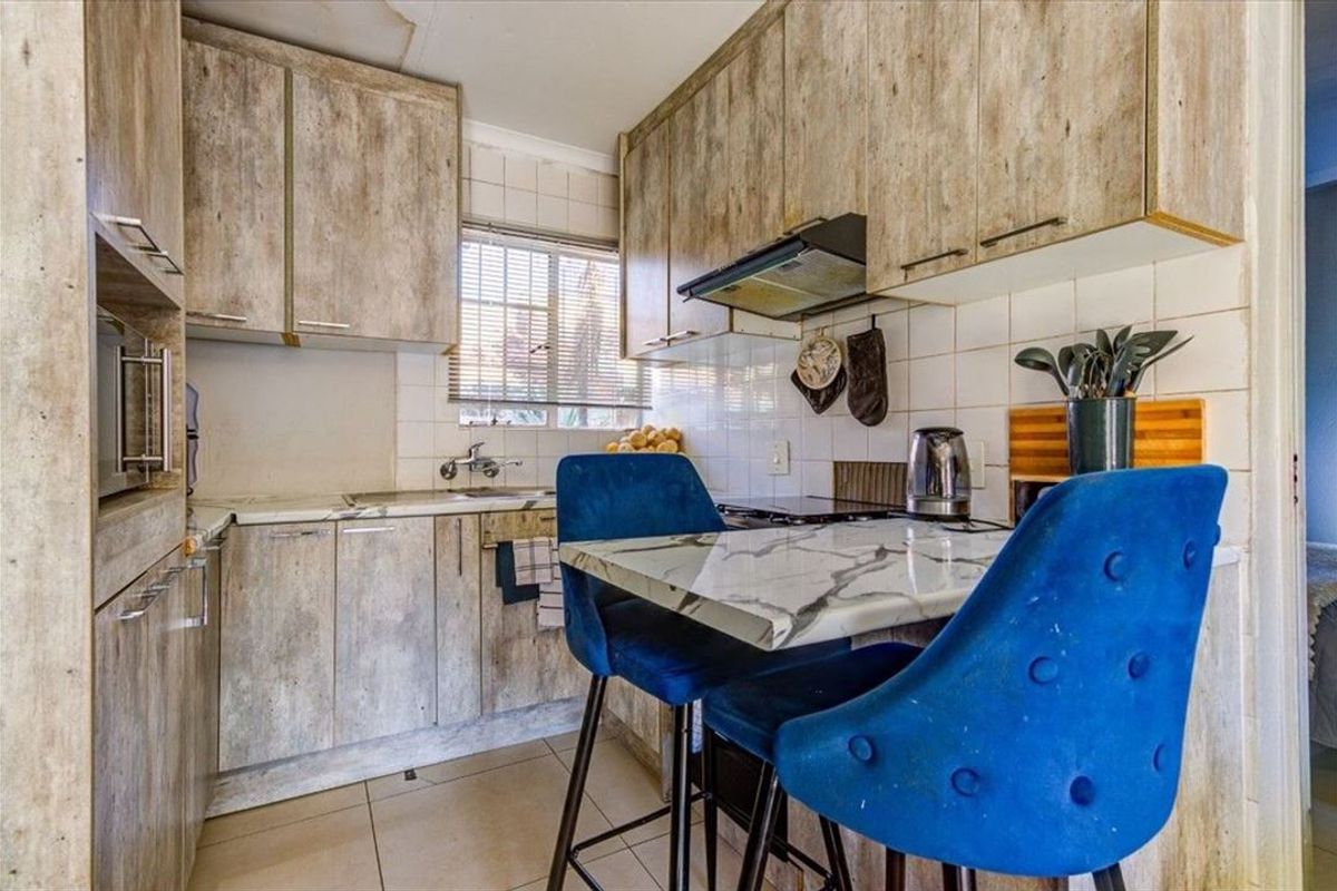 Compact kitchen featuring wood-look cabinetry, tiled backsplash, built-in oven, and hob, providing a functional workspace with integrated storage solutions.