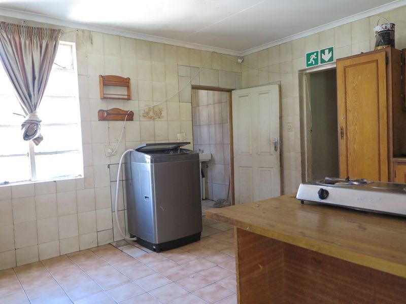 A functional kitchen space featuring tiled walls, tiled flooring, and built-in wooden cabinetry, offering potential for modernization and renovation.