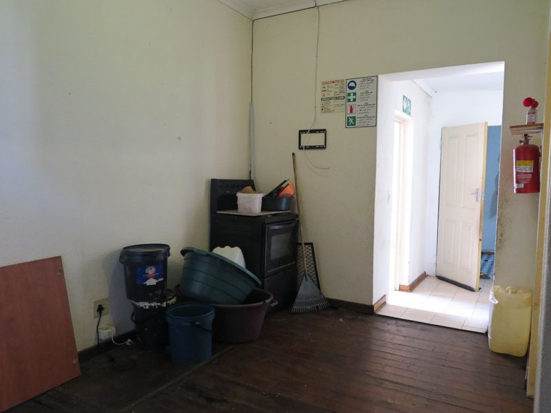 A utility space featuring timber flooring, a freestanding stove, and direct access to an adjacent room. The area requires maintenance and cosmetic updates.